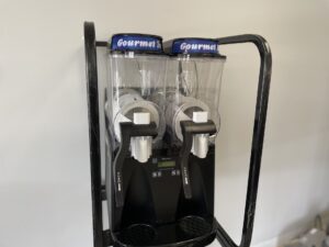 Two beverage dispensers on a stand in front of a wall.