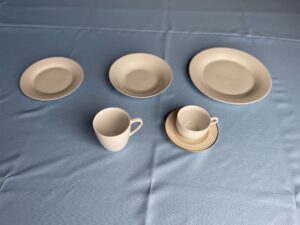 A set of white plates and cups on a blue tablecloth.